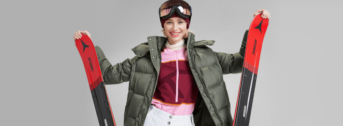 Vrouw met ski-kleren aan en een ski in beide handen