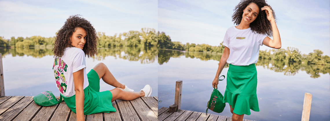 Vrouw zittend aan het water met groen rokje, wit shirt en een groen tasje