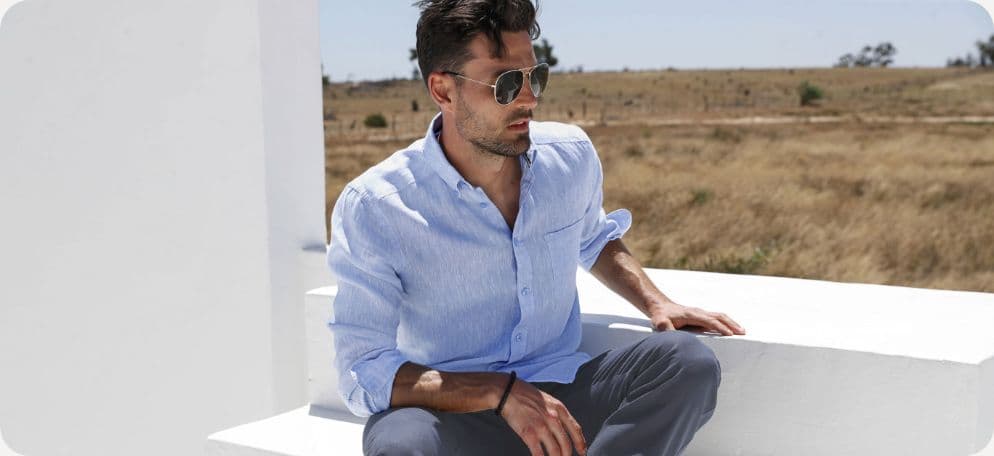 Man met blauw blouseje en een horloge zittend op witte verhoging