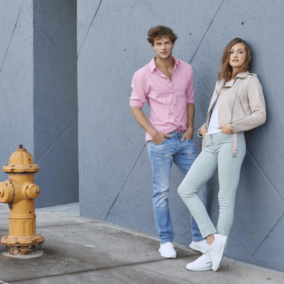 Man en vrouw tegen de muur aan met pastel kleurige kleren
