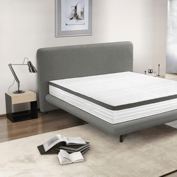Slaapkamer met een bed dat niet is opgemaakt en boeken op de grond