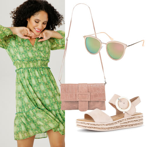 Vrouw in een groene wikkeljurk met verschillende accessoires die erbij passen ernaast horend bij een festival outfit