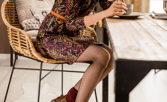 Vrouw zittend aan tafel die koffie drinkt met panty's aan