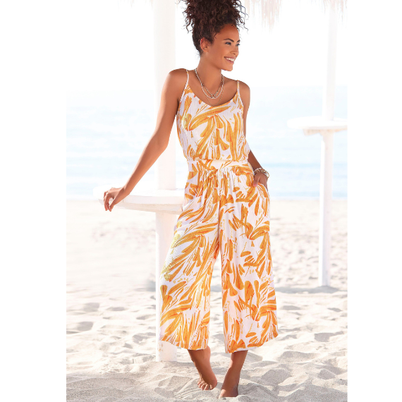 Vrouw op het strand met een oranje/witte jumpsuit