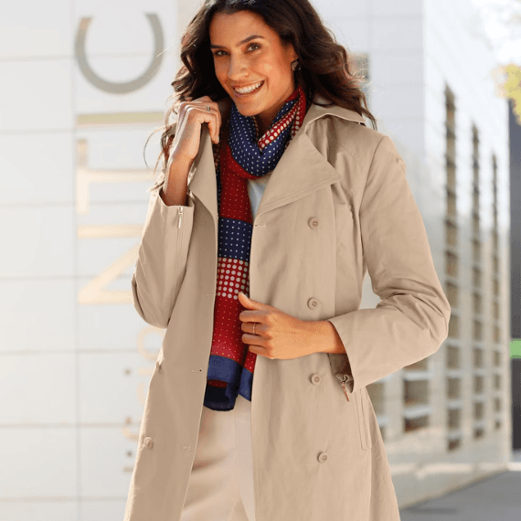 Vrouw in de stad met een sjaal en een trenchcoat aan